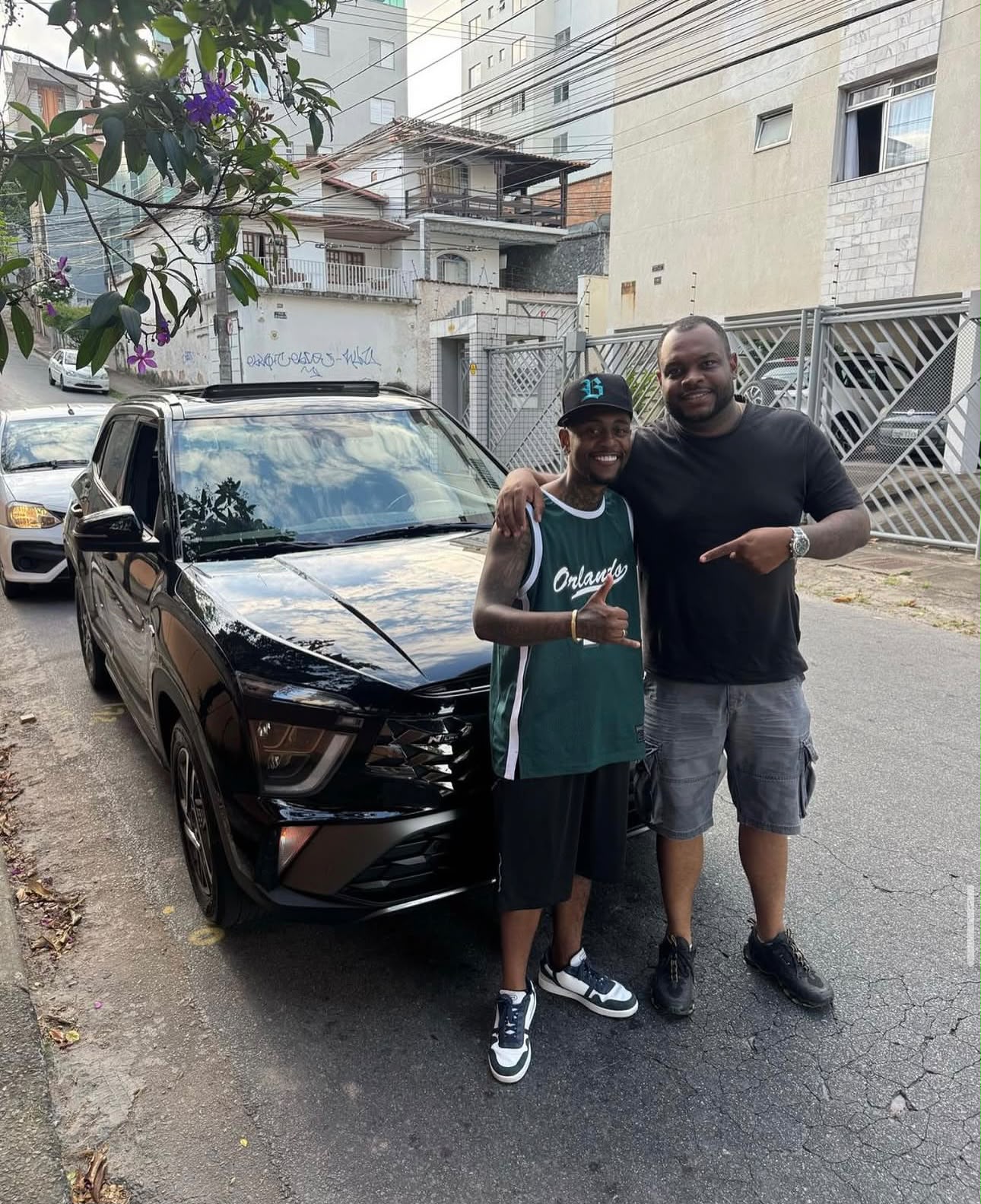 Cliente ao lado do seu SUV preto com o consultor da FM Consórcios