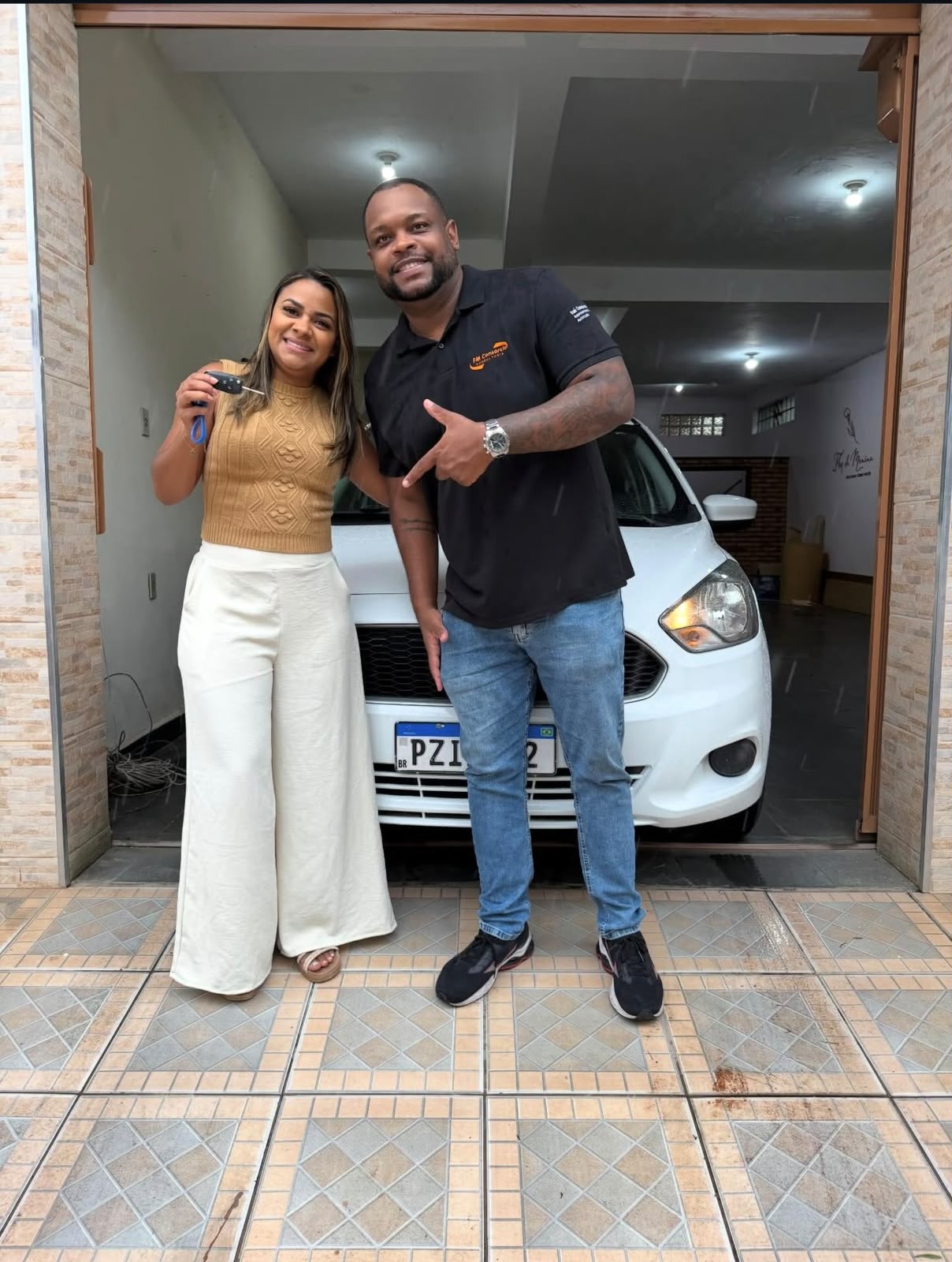 Cliente segurando a chave do carro branco entregue pela FM Consórcios